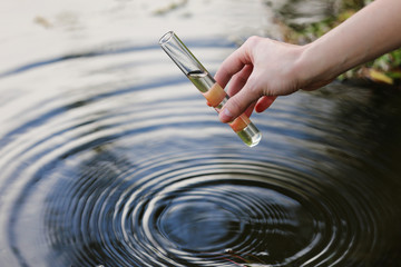 Water sample. Hand collects water to explore. Concept - water purity analysis, environment,...