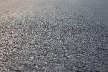 Sloped texture of new black asphalt road, perspective