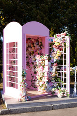 Pink phone booth decorated colourful flowers. Elegant wedding photo zone outdoor. Beautiful...