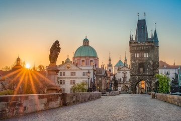 Sun rays filling the scene with colors during sunrise on empty deserted Charles bridge in Prague, Czech Republic