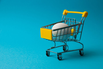 Egg in a yellow grocery cart on a blue background