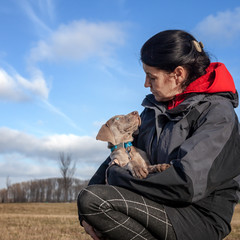 Frau mit einem Weimaraner Welpe auf dem Arm genießt die schöne Zeit