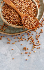 Raw dry buckwheat grain  in a bowl with a spoon