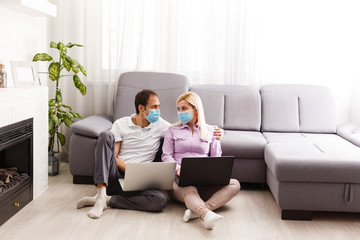 Obraz premium A young family works from home using computers. Couple working remotely online while on quarantine. Stay at home concept. Corona virus covid-19 pandemic outbreak. Freelance work