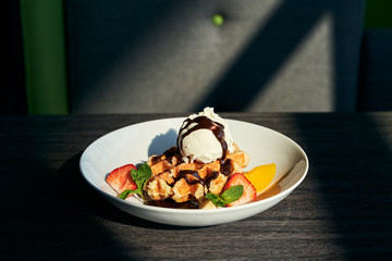 Belgian waffle with ice cream, strawberries, orange and chocolate