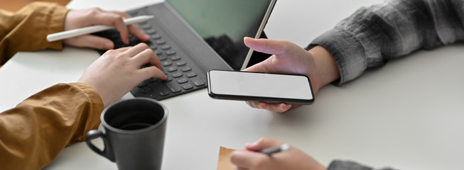 Cropped shot of businesspeople working on tablet and mock-up smartphone