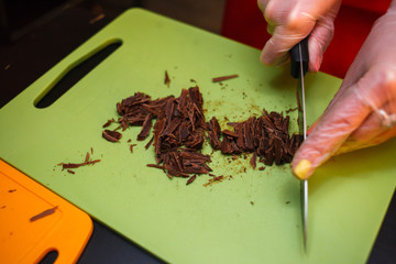 Close up of a woman hands chopping chocolate block for brownie cake
