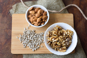 cuenco de almendras y nueces con pipas sobre tabla de madera