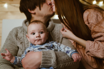 traditional married couple with a baby in the arms of a dad kissing on the lips of the baby mom