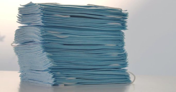 Close-up of blue medical masks on the table. Camera moving up along stack of protective antiviral masks. Covid-19 pandemic, transmissible disease, coronavirus lockdown, quarantine. Cinema 4k ProRes HQ