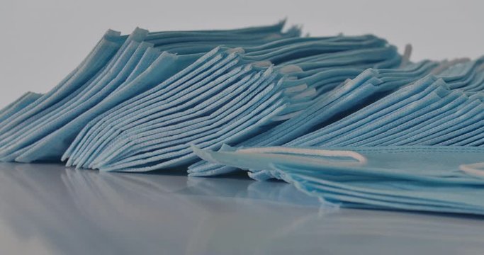 Lot of face masks lying on the table as camera moving to the left. Close-up stack of protective antiviral masks. Coronavirus, Covid-19, medicine, health care, flu. Cinema 4k ProRes HQ.