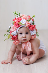 portrait of a baby girl in a hat made of roses