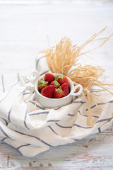 Fragole in una tazzina su sfondo di legno