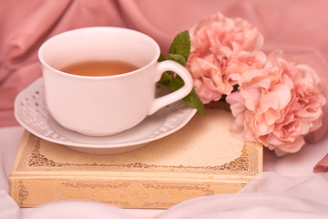 Pausa relax con libro, tè caldo e peonie rosa