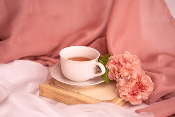 Pausa relax con libro, tè caldo e peonie rosa