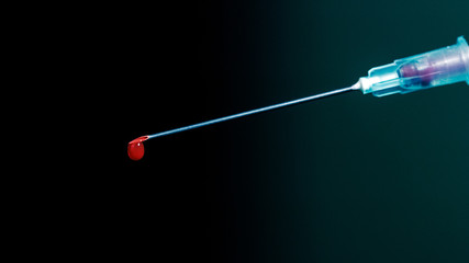 Syringe with blood isolated on dark background, closeup