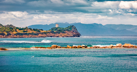 Fototapeta premium Panoramic morning view of Torre di San Macario tower from Nora beach. Colorful summer scene of Sardinia island, Italy, Europe. Bright seascape of Mediterranean sea. Traveling concept background.