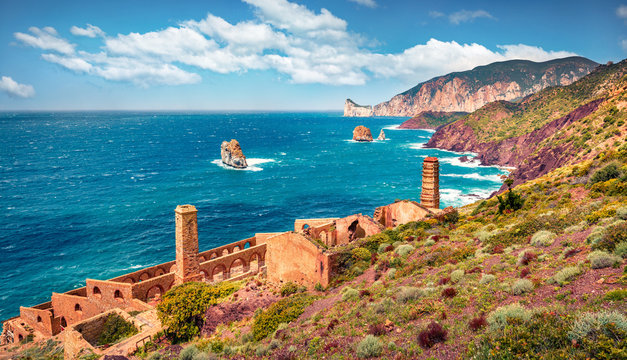 Stunning summer view of ancient ruins of Laveria Lamarmora (Miniera di Nebida) with Porto Corallo on background. Nice morning scene of Sardinia, Italy, Europe. Mediterranean seascape.