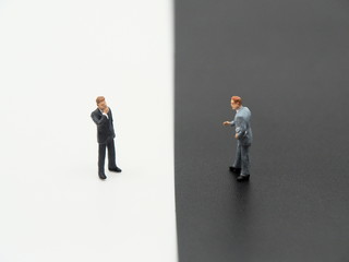 A miniature businessman on  white background and a miniature businessman on black background.Debate concept image.
