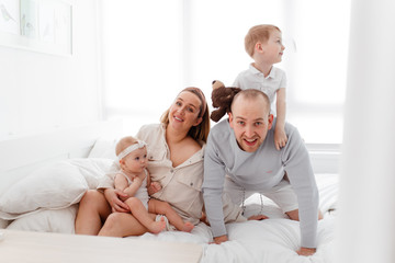 Obraz premium A young happy family with young children lying around, hugging, laughing on the bed at house