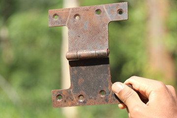 Rusty hinge used to open and close door held in hand