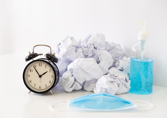 Alarm clock with crumpled paper concept, for wasting time from coronavirus, prevention of initial outbreaks with the use of face mask and hand sanitizer gel.