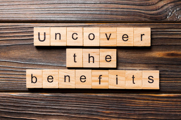 uncover the benefits word written on wood block. uncover the benefits text on table, concept
