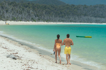 Couple on honeymoon on beach, walking on white sand, with aqua turquoise ocean. Travel, holiday, vacation, romantic, paradise, exotic. Whitsundays Islands, Queenstown, Australia.