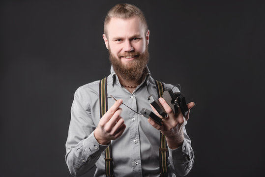 Handsome young man presents car parts on a gray background. The concept of sales and testing of goods