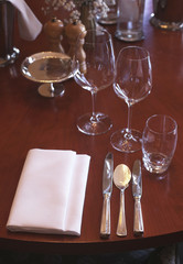 Beautiful classy table setting for fine dining at a high end restaurant. Fancy luxury tableware for celebration. Glasses, spoons, forks, knives, napkins. Luxury lifestyle. 