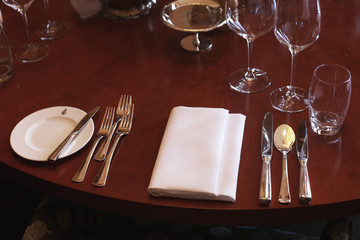 Beautiful classy table setting for fine dining at a high end restaurant. Fancy luxury tableware for celebration. Glasses, spoons, forks, knives, napkins. Luxury lifestyle. 