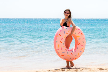 Naklejka na ściany i meble Full length portrait of attractive woman holding doughnut inflatable ring on the beach at the sea background. Have happy summer