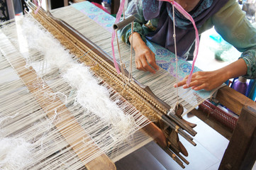 A woman is using traditional weaving machines to weave songket. Songket is a Malay traditional clothes with high quality and value.