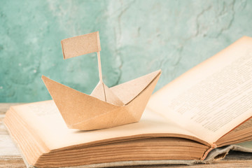 paper boat on an old book on a table