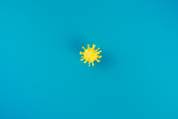 Yellow coronavirus symbol on the blue background in the center. Copy space, medical background. 