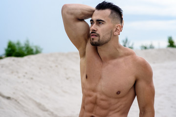 sexy man, white macho macho man lying on white sand against sky background, white empty beach...