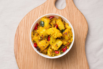 Aloo gobi traditional Indian dish of vegetables and spices in a bowl on a wooden board