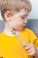 Little blond boy with a wooden toothbrush