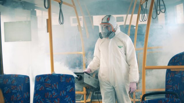 Disinfector is fumigating bus interior with a special machine