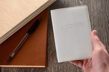 Hand holding a passport. Books in the background