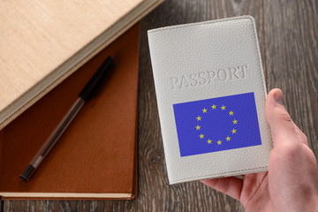 Hand holding a EU passport. Books in the background