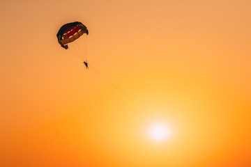 Parasailers Flying On Colorful Parachute In Sunset Sunrise Sky. Active Hobby. Sunshine