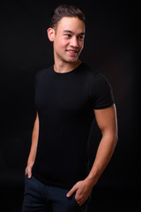 Young handsome multi ethnic man against black background