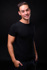 Fototapeta premium Young handsome multi ethnic man against black background