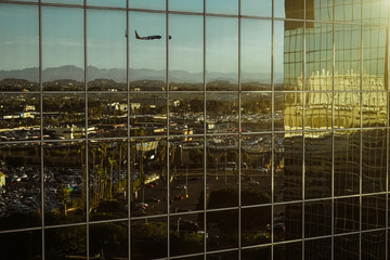 Spiegelung eines Flugzeuges in der Glasfassade eines Gebäudes in Los Angeles