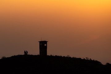 silhouette of two people with a watchtower in athens