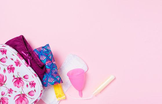 Copa menstrual de silicona. Neceser con art&iacute;culos de higiene &iacute;ntima para la menstruaci&oacute;n como compresa, tamp&oacute;n y copa menstrual. Salud de la mujer e higiene alternativa. Fondo rosa