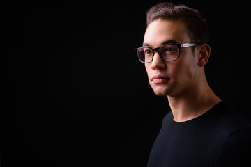 Fototapeta premium Young handsome multi ethnic man against black background