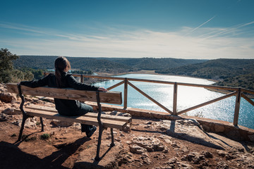 mujer sentada en un banco de madera mirando al horizonte