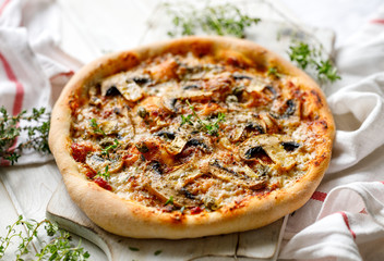 Mushroom pizza with parmesan cheese and herbs on a white board close up